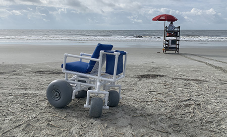 Beach Wheelchair on beach in front of Lifeguard stand