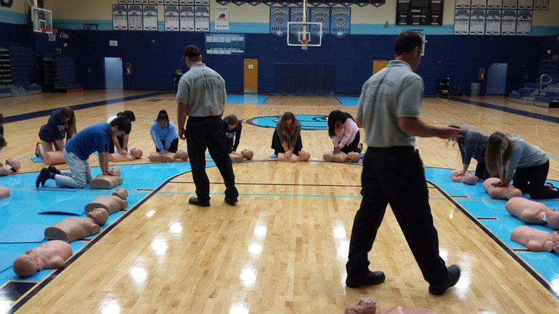 Firefighters instructing students with CPR dummies