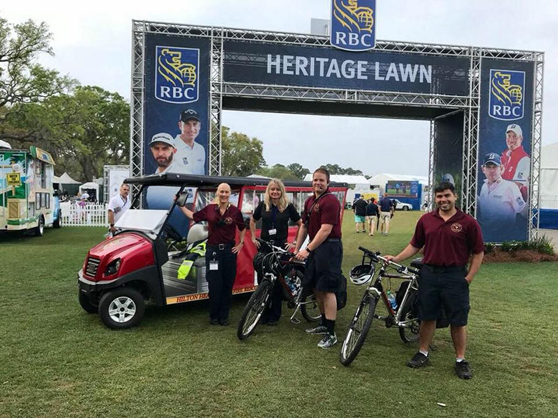 Fire Rescue staff on golf cart and bikes in front of the Hertiage Lawn sign