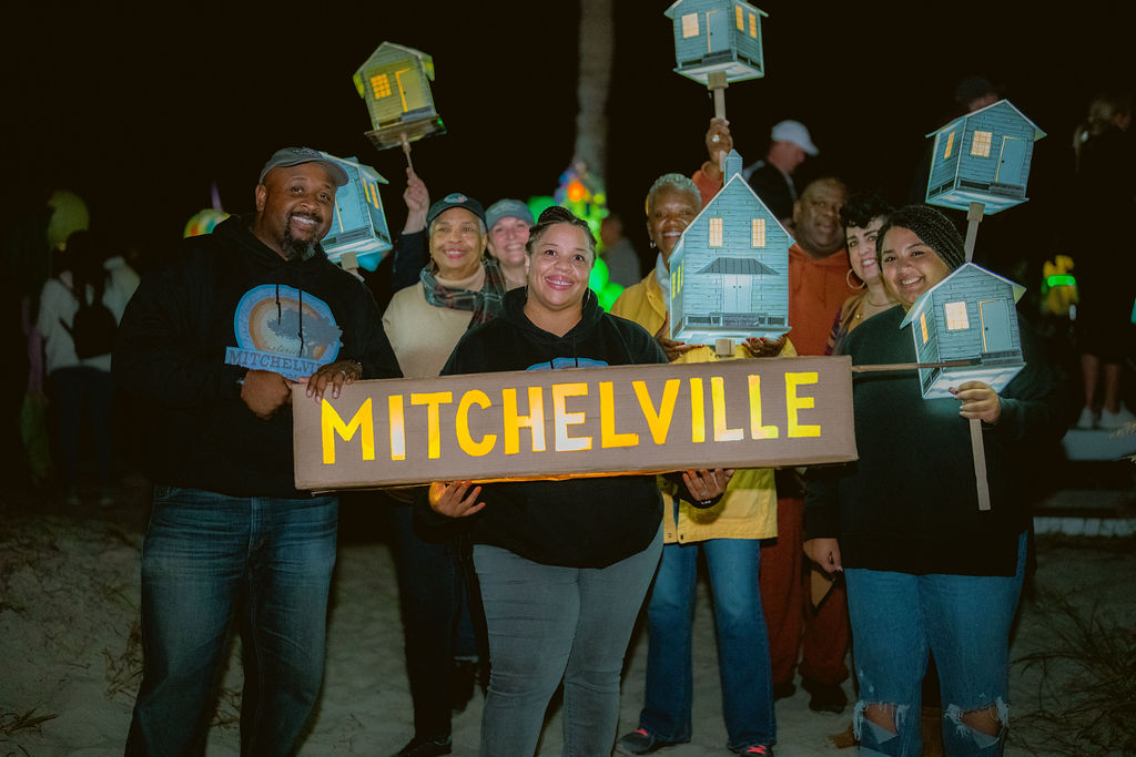 Mitchville sign and Laterns held by participants