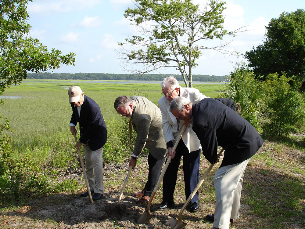 Four men with shovels with marsh in the background