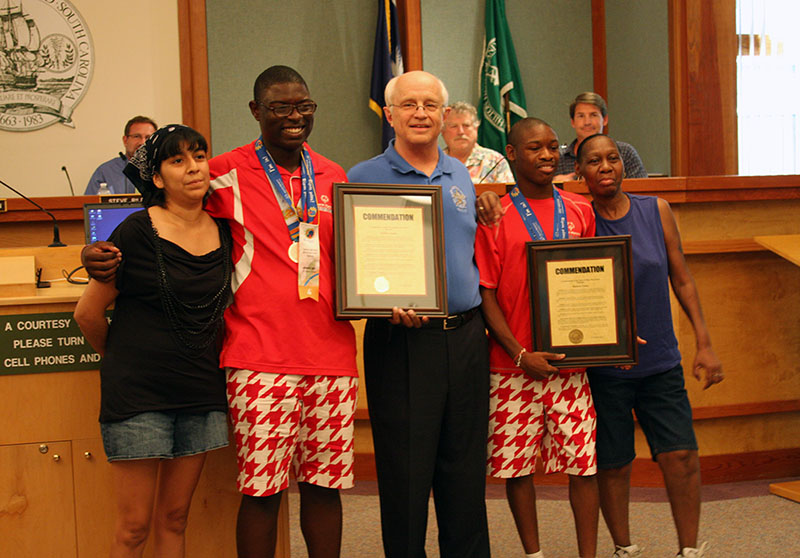 Two Special olympians with Mayor Laughlin holding commendations