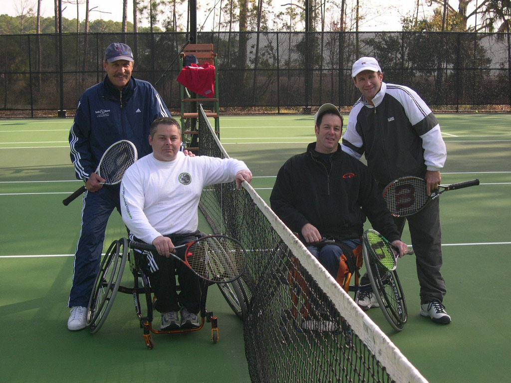 Tennis players standing and in wheelchairs at net